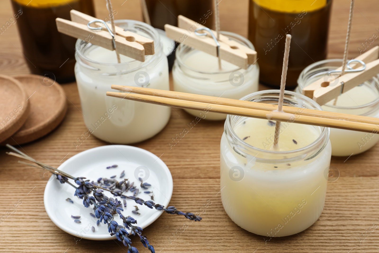 Photo of Glass jars with wax on wooden table. Handmade candles