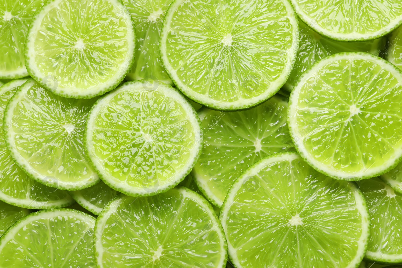 Photo of Fresh sliced ripe limes as background, top view