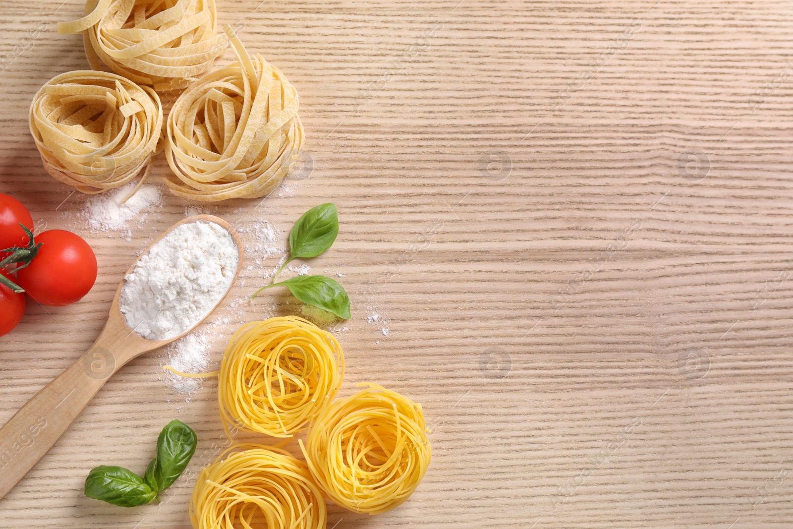 Photo of Flat lay composition with different types of pasta on wooden background. Space for text