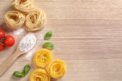 Flat lay composition with different types of pasta on wooden background. Space for text