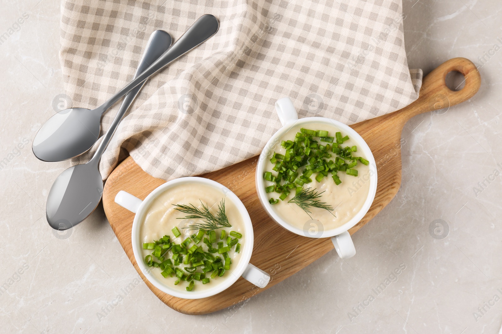 Photo of Bowls with tasty creamy soup of parsnip served on light grey table, flat lay