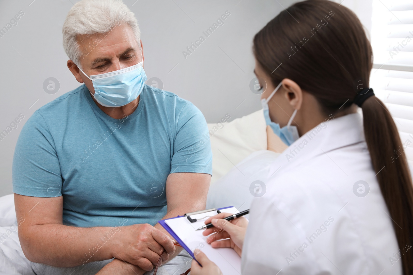 Photo of Doctor examining senior man with protective mask at nursing home