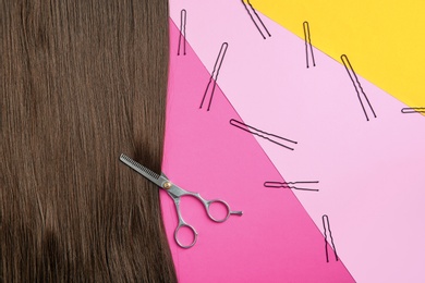 Flat lay composition with brown hair, scissors and pins on color background