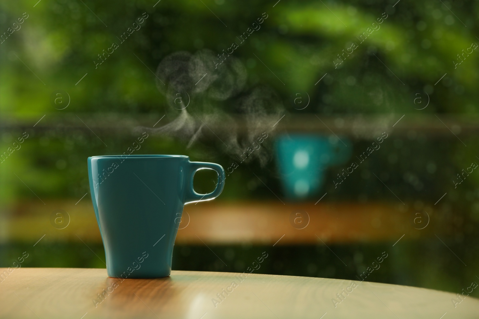 Photo of Cup of hot drink on wooden table against blurred background, space for text