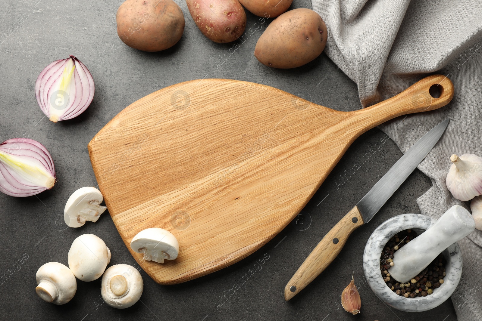 Photo of Flat lay composition with wooden cutting board and products on dark textured table