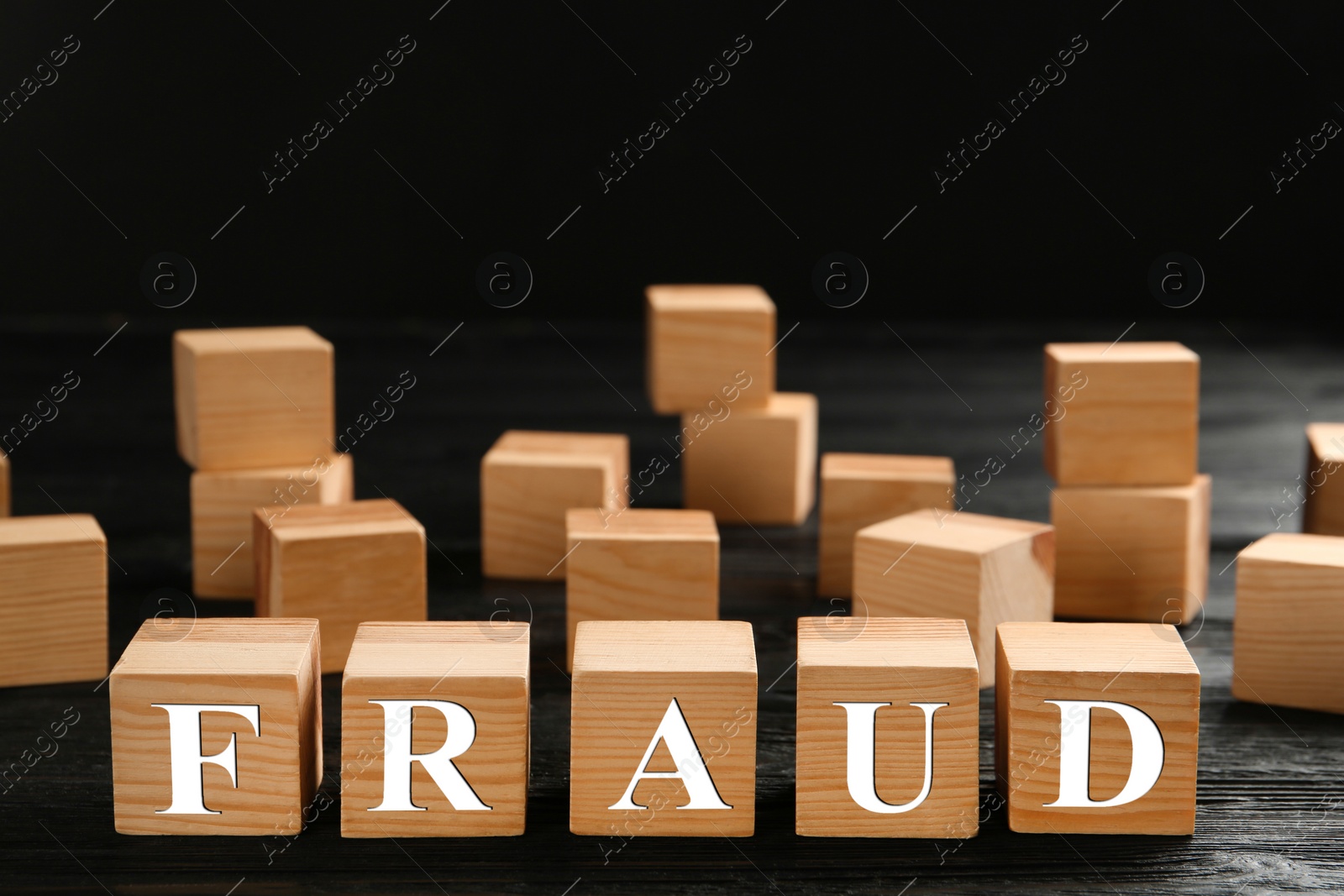 Photo of Wooden cubes with word Fraud on black table, space for text