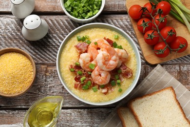 Photo of Fresh tasty shrimps, bacon, grits and green onion in bowl on wooden table, flat lay