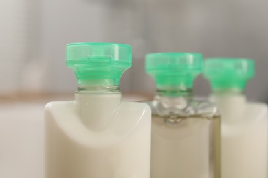 Photo of Mini bottles of cosmetic products on blurred background, closeup