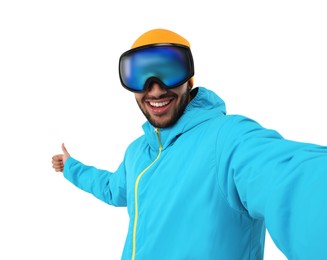 Photo of Smiling young man in ski goggles taking selfie and showing thumbs up on white background