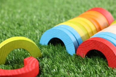 Photo of Colorful wooden pieces of play set on green grass, closeup. Educational toy for motor skills development