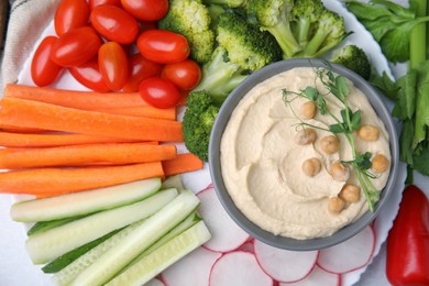 Plate with delicious hummus and fresh vegetables on table