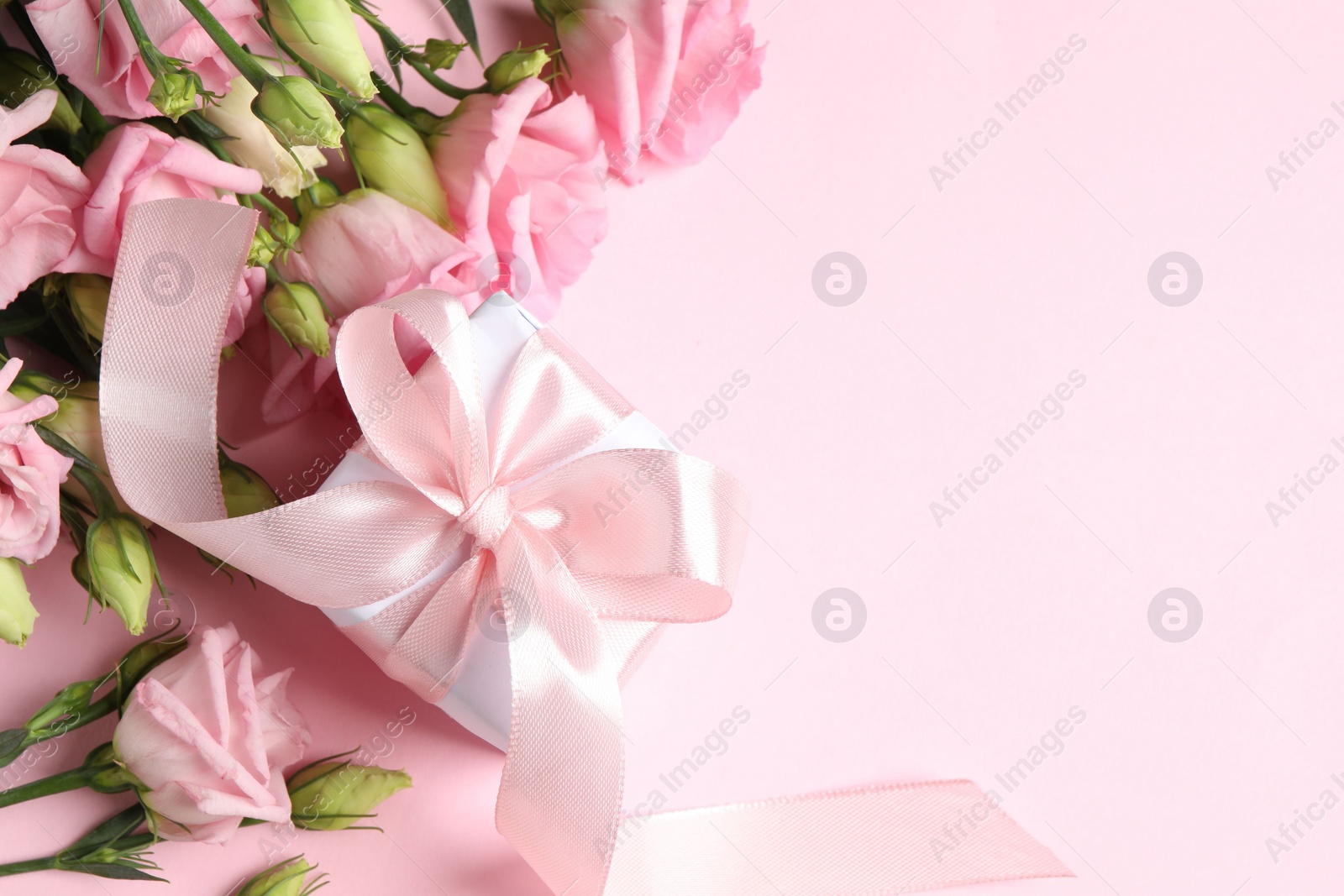 Photo of Happy Mother's Day. Beautiful flowers and gift box on pink background, flat lay. Space for text