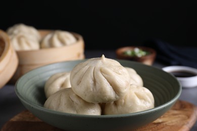 Delicious bao buns (baozi) in bowl on grey table, closeup