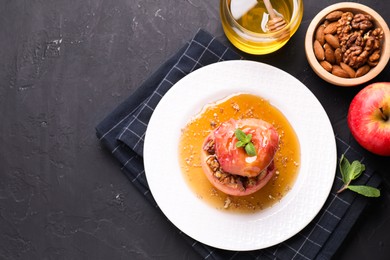 Photo of Tasty baked apple with nuts, honey and mint on gray textured table, flat lay. Space for text