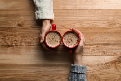 Photo of Women with cups of coffee at wooden table, top view