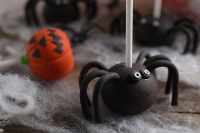 Different Halloween themed cake pops on wooden table, closeup