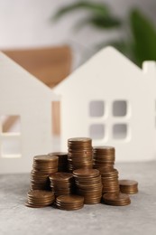 House models and stacked coins on grey table, selective focus