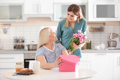Photo of Daughter congratulating happy mature woman on Mother's Day at home