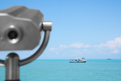 Photo of Metal tower viewer and picturesque view of sea with boat. Mounted binoculars