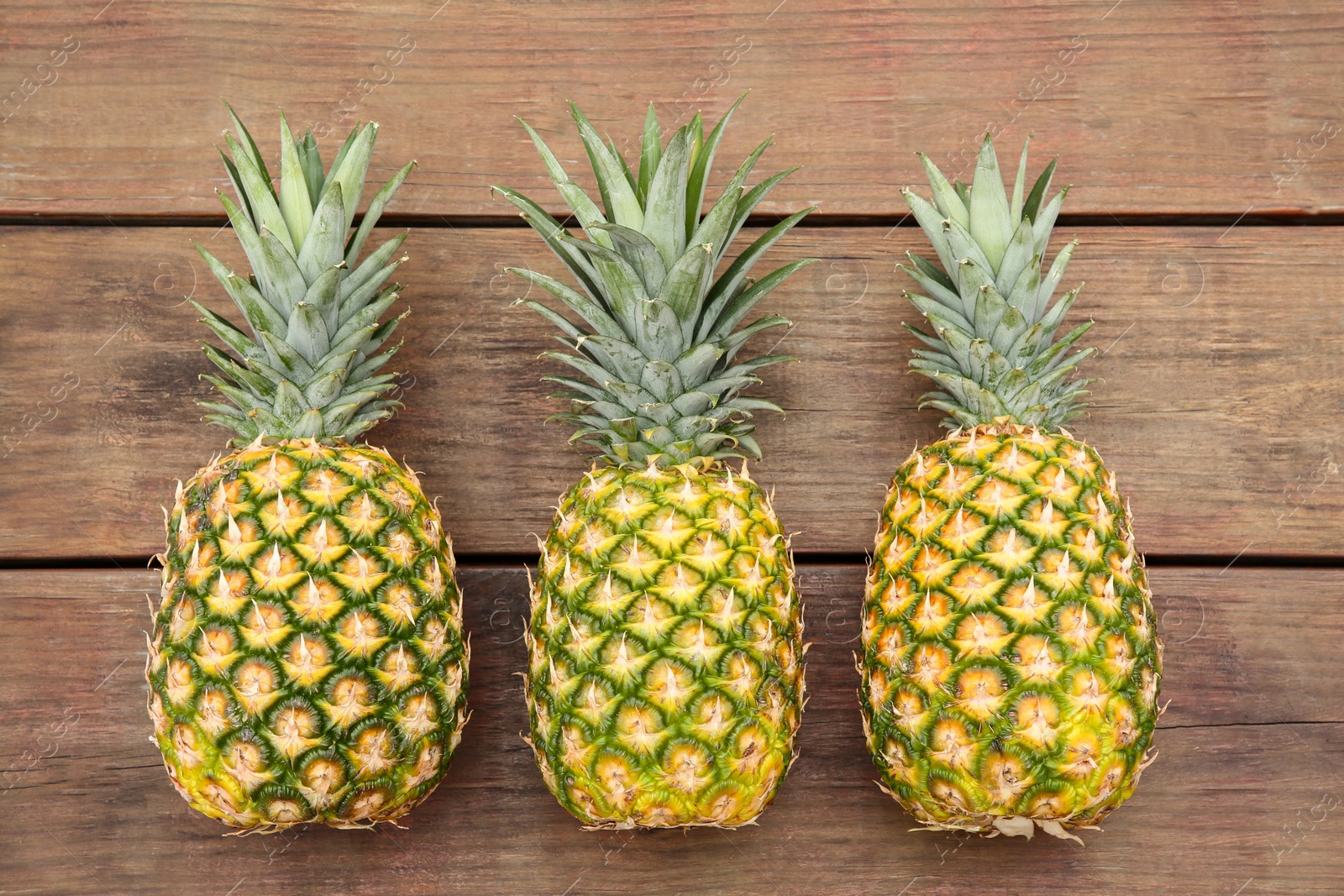 Photo of Delicious ripe pineapples on wooden table, flat lay