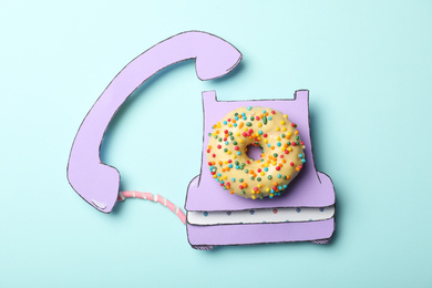 Photo of Vintage phone made with donut on light blue background, top view