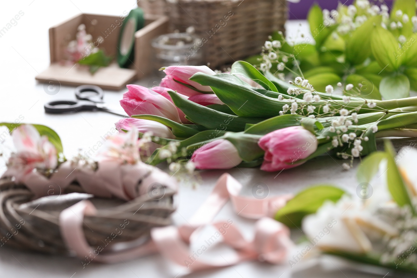 Photo of Decorator's workplace with unfinished wreath and beautiful flowers