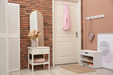 Photo of Hallway interior with mirror and white furniture. Stylish accessories