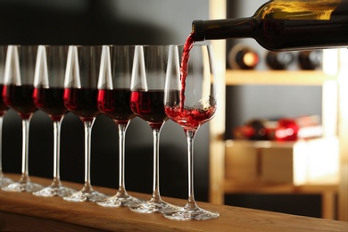 Photo of Pouring wine from bottle into glass in cellar