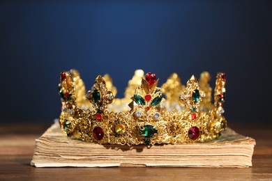Beautiful golden crown on old book against dark blue background. Fantasy item