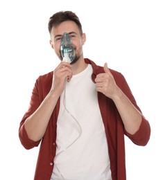 Man using nebulizer for inhalation and showing thumb up on white background