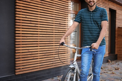 Man with bicycle on street near wooden wall, closeup