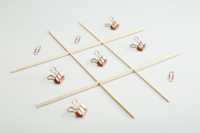 Photo of Tic tac toe game made with paper clips on light background