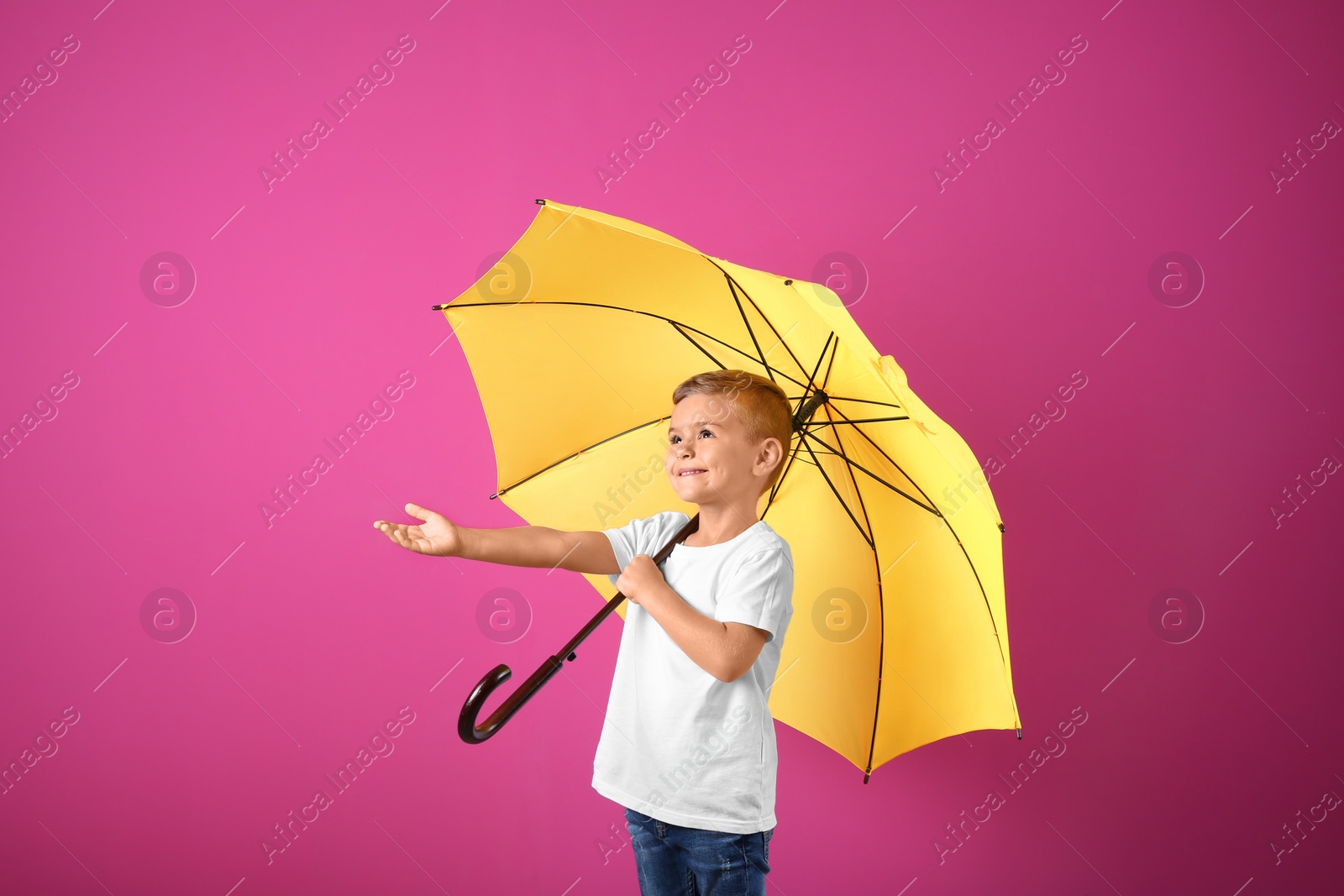 Photo of Little boy with yellow umbrella on color background