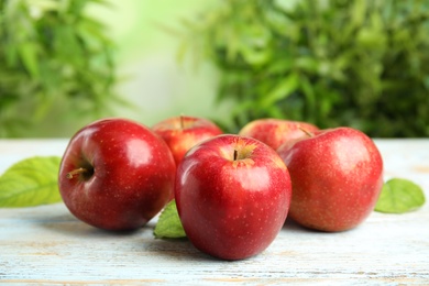 Ripe juicy red apples on white wooden table against blurred background. Space for text