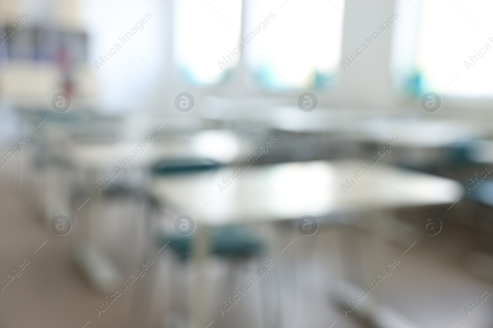 Photo of Blurred view of empty school classroom with desks, windows and chairs