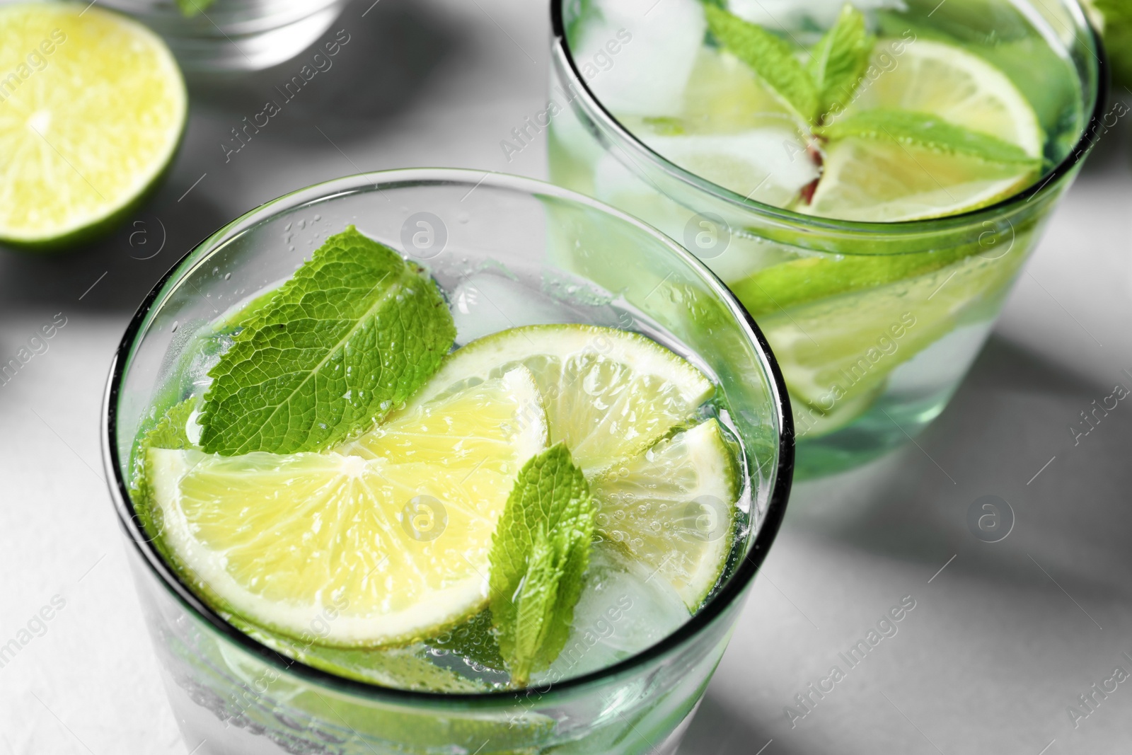 Photo of Refreshing beverage with mint and lime in glasses on table, closeup