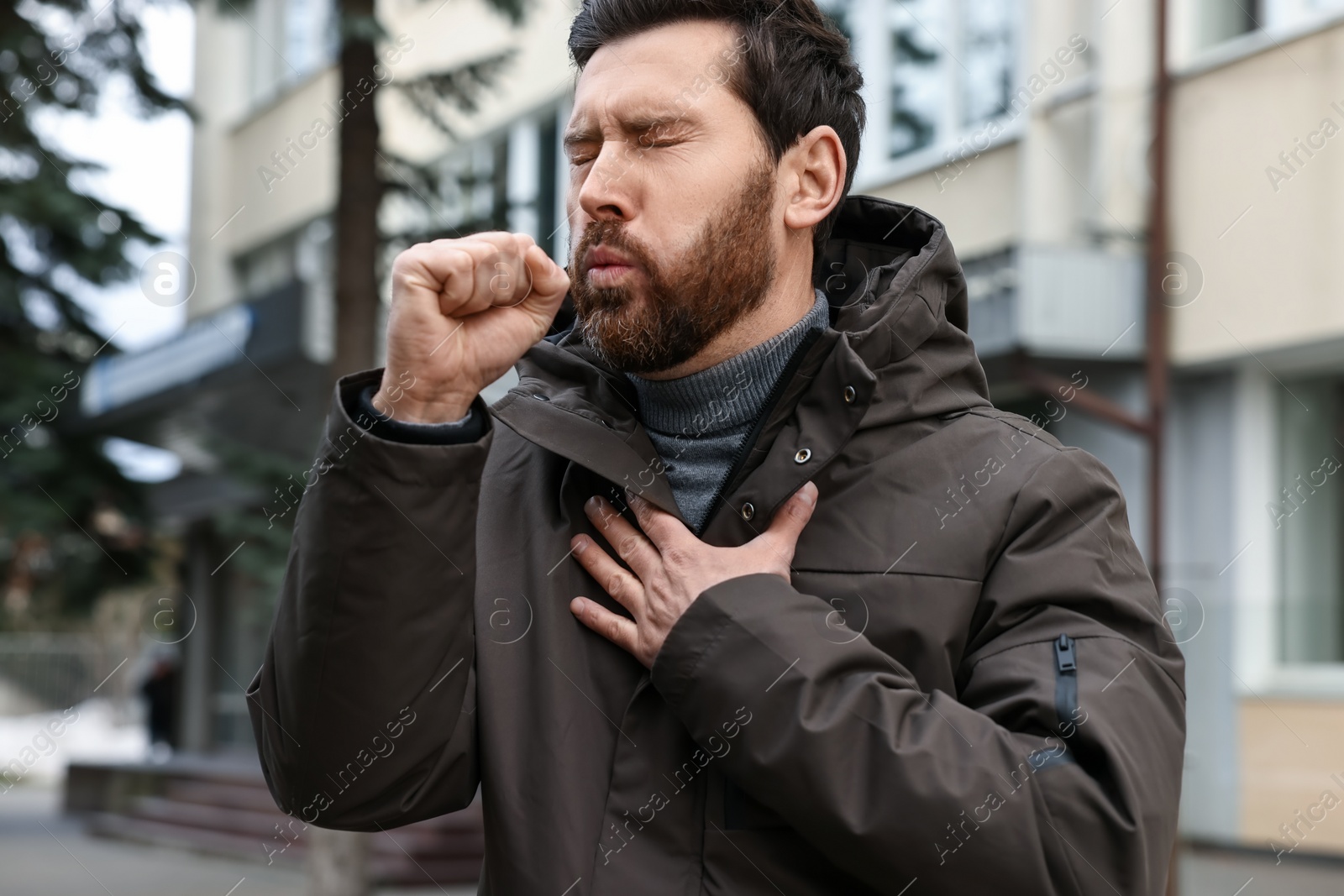 Photo of Sick man coughing on city street. Cold symptoms