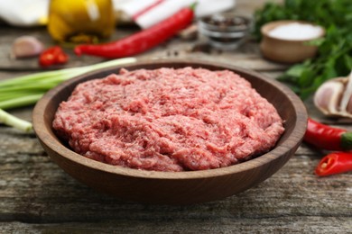 Bowl with raw fresh minced meat on wooden table, closeup