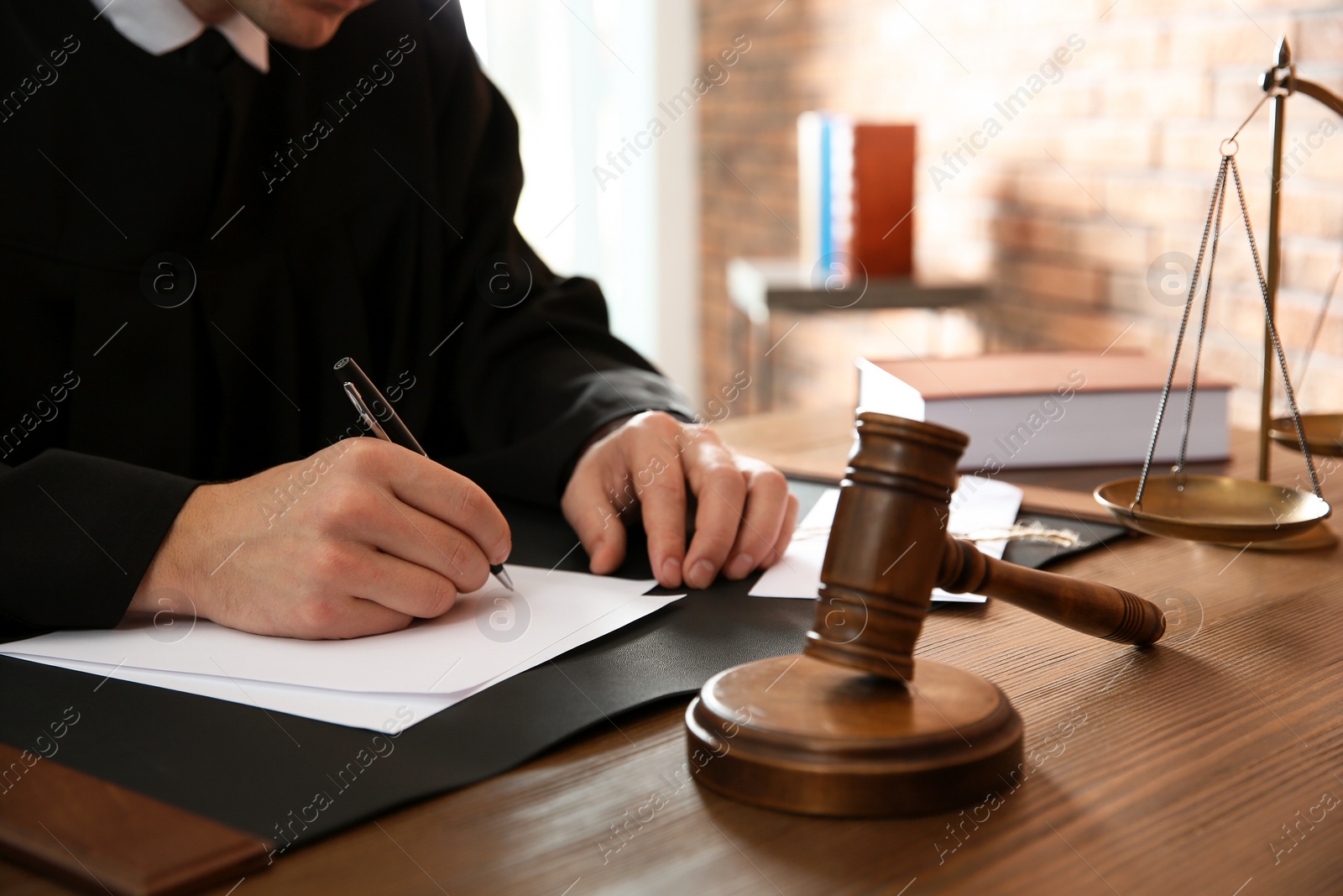 Photo of Judge working with papers and gavel on table, closeup. Law and justice concept