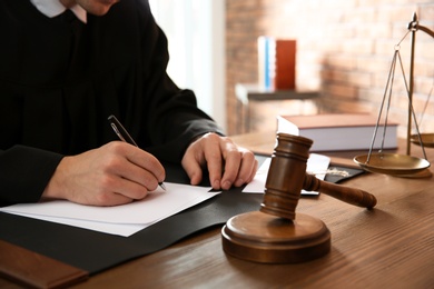 Judge working with papers and gavel on table, closeup. Law and justice concept