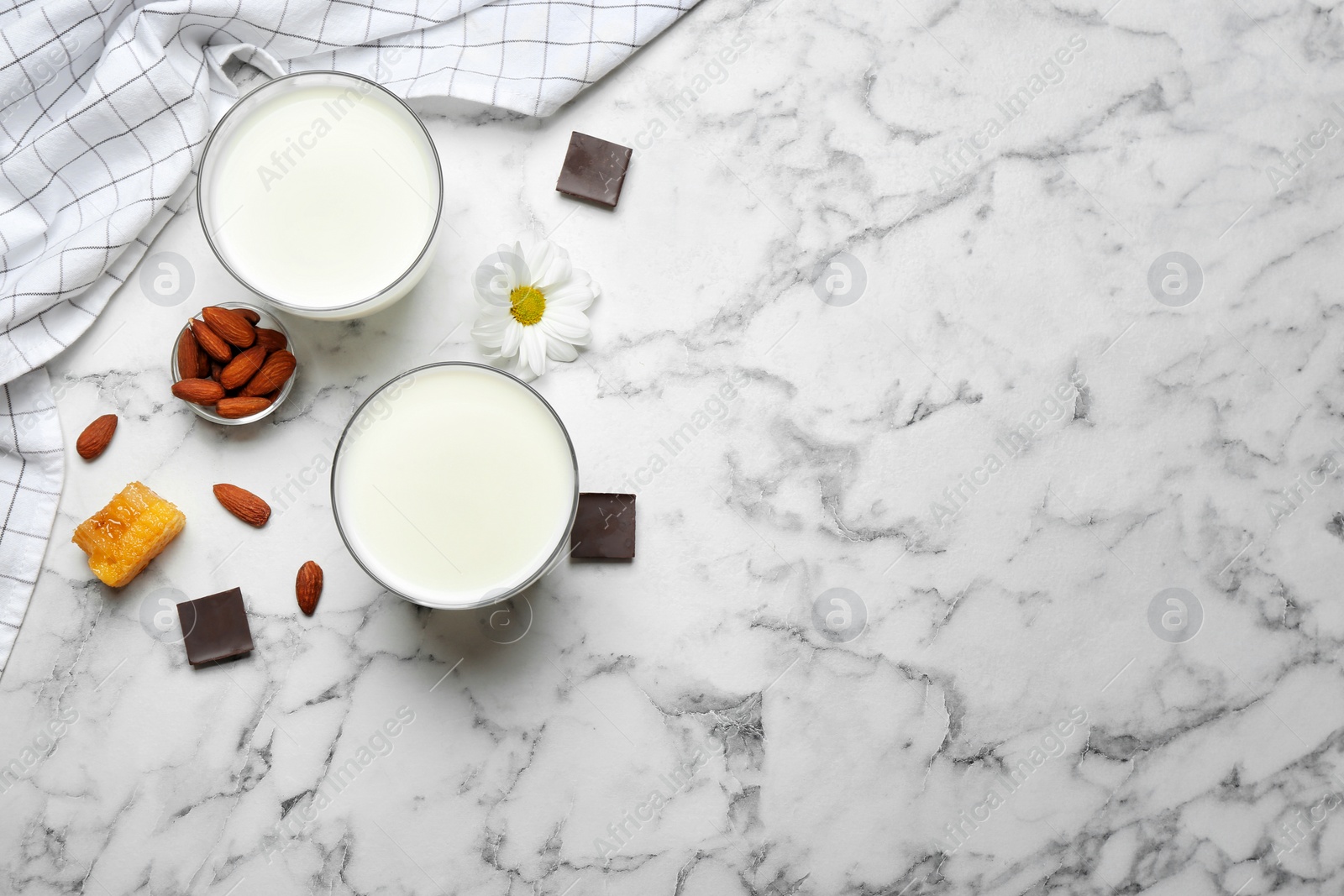 Photo of Glasses with milk, nuts and chocolate pieces on light background