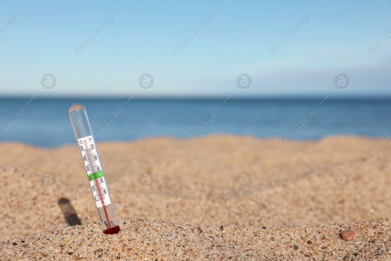 Photo of Weather thermometer in sand near sea, space for text