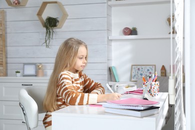 Photo of Cute little girl with modern tablet studying online at home. E-learning