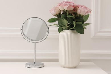 Photo of Mirror and vase with pink roses on white dressing table