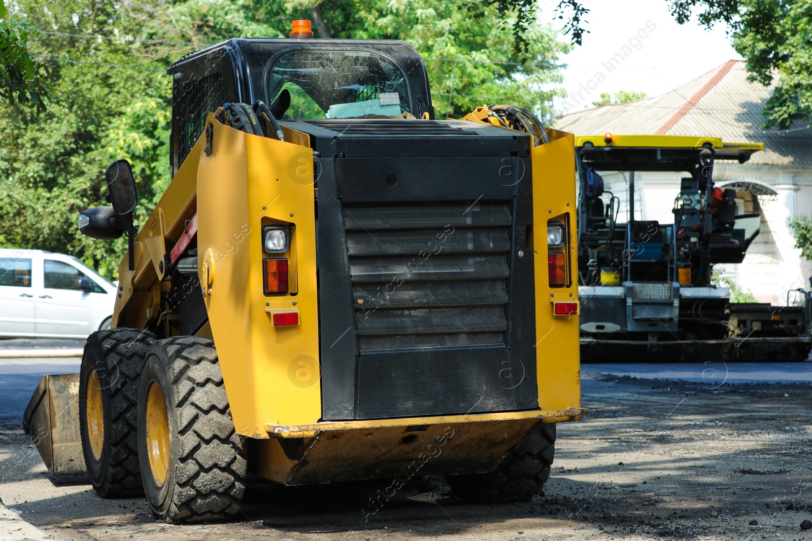 Photo of Modern skid loader on city street. Road repair service