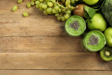 Glasses of fresh green smoothie and ingredients on wooden table, flat lay. Space for text