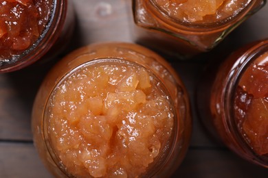 Delicious apple jam in jars on wooden table, flat lay