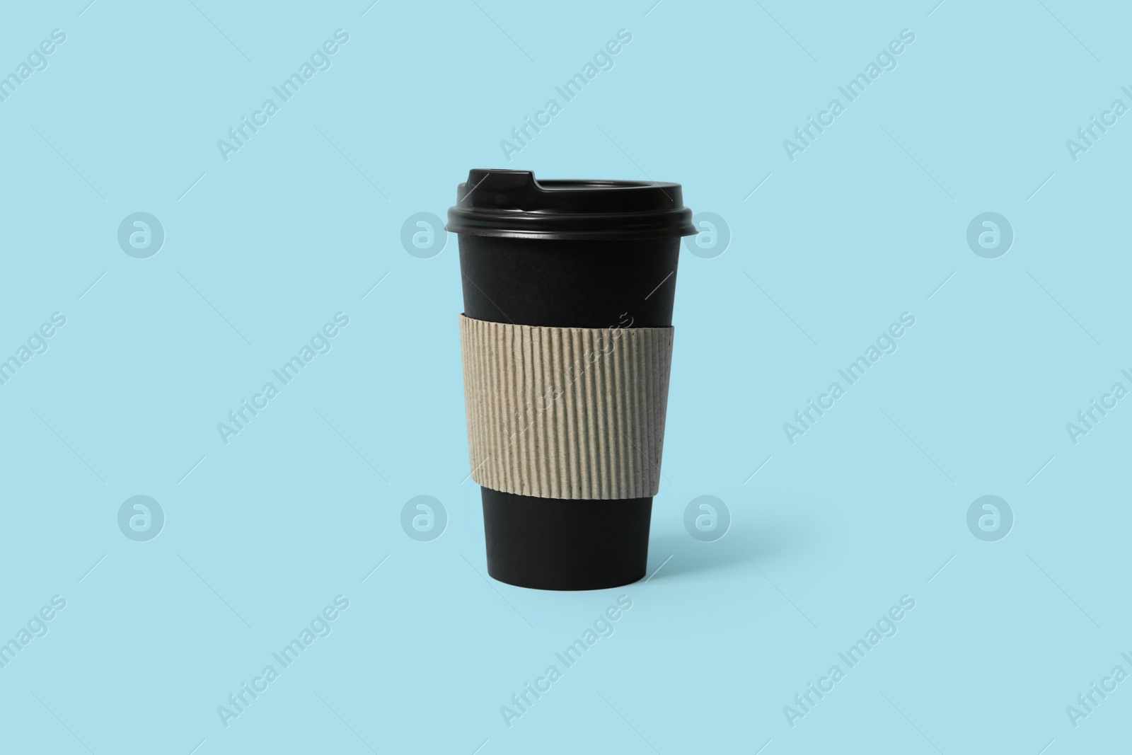 Photo of Takeaway paper coffee cup with cardboard sleeve on light blue background