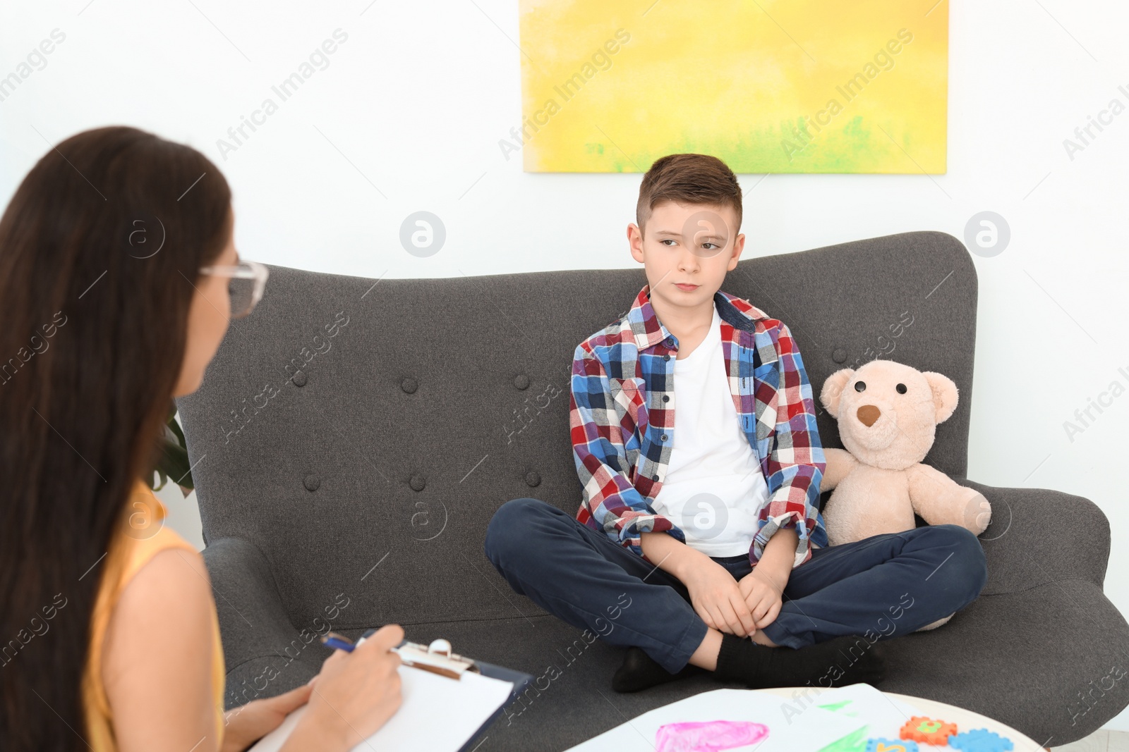 Photo of Child psychologist working with boy in office