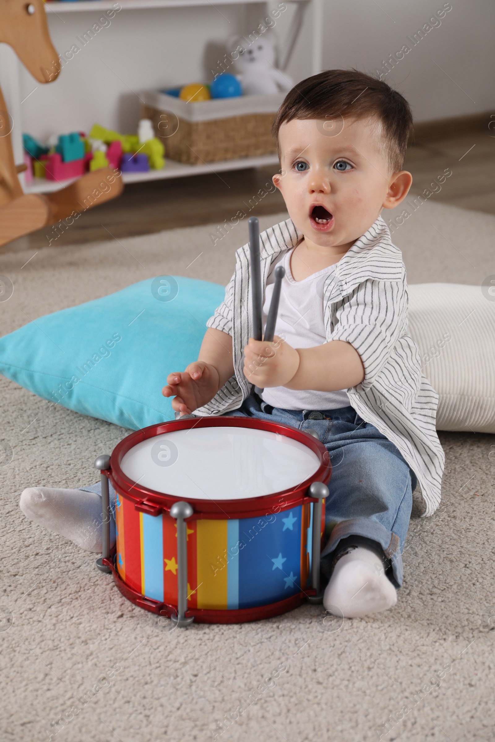 Photo of Cute little boy with toy drum and drumsticks at home